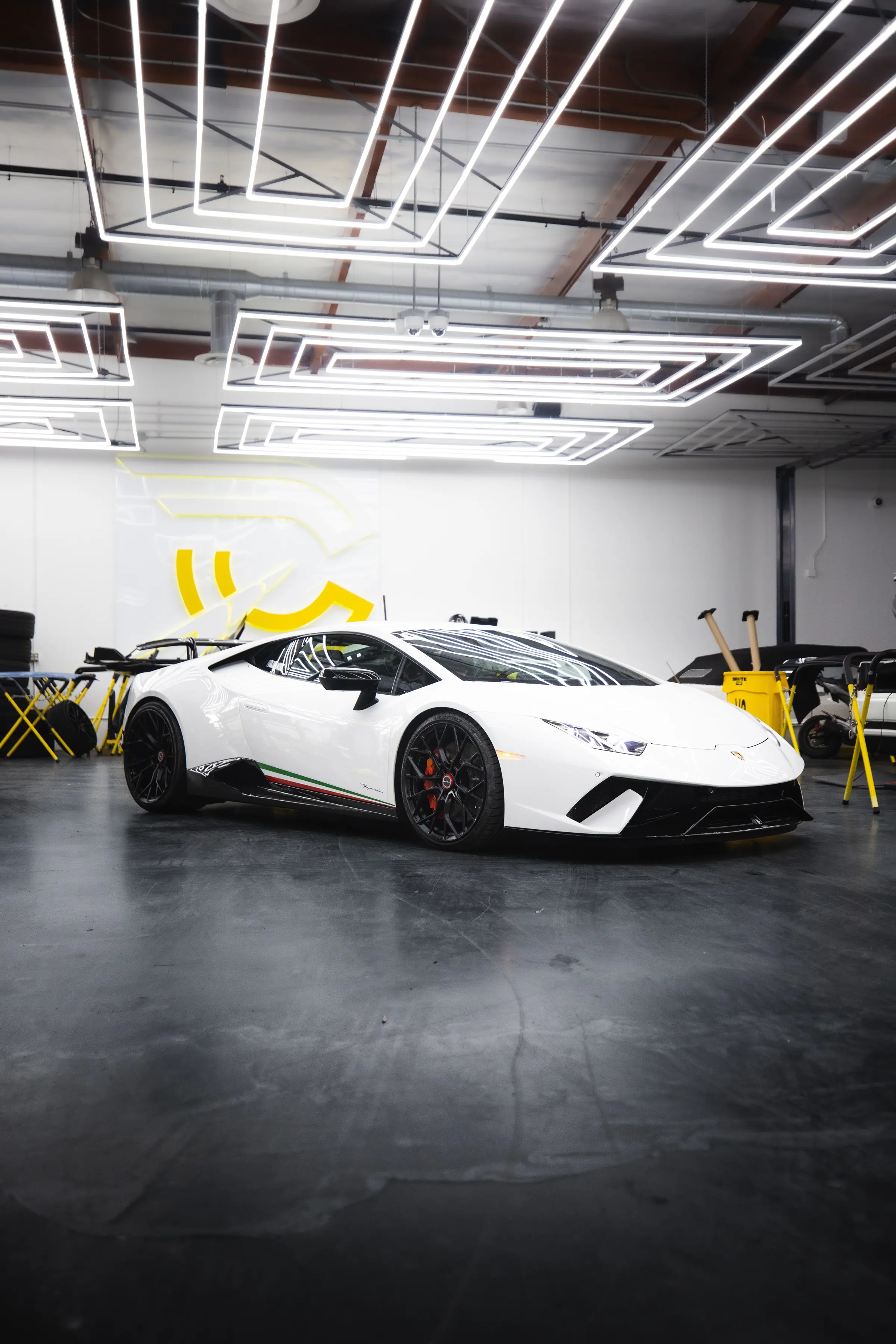A white Lamborghini Huracán under rows of LED strip lights